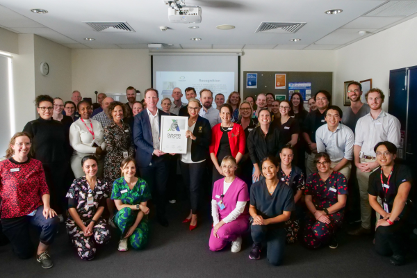 Austin Health Stroke Unit with CEO (Interim) Cameron Goodyear and Angels Initiative representative Samantha Dagasso holding framed certificate of WSO Angels Diamond Award awarded to Austin Health for excellence in stroke care.